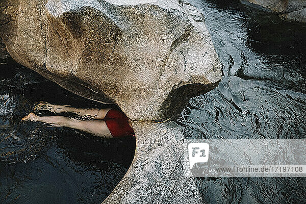 Frau in Rot schwimmt durch einen Steindurchgang