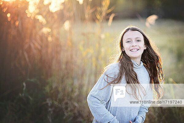 Backlit beautiful young tween girl with long hair outdoors in Fall.