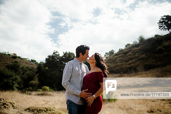Ehemann und schwangere Frau posieren auf einem Feld in San Diego