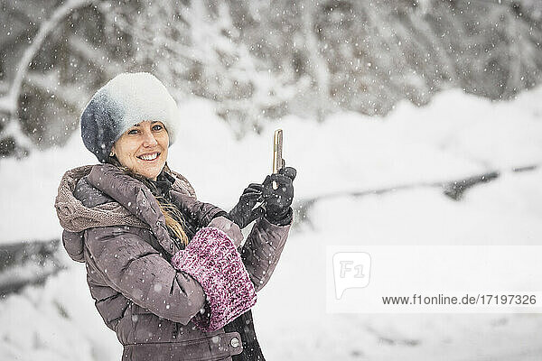 woman with snow cap taking a selfie in the middle of a snowfall