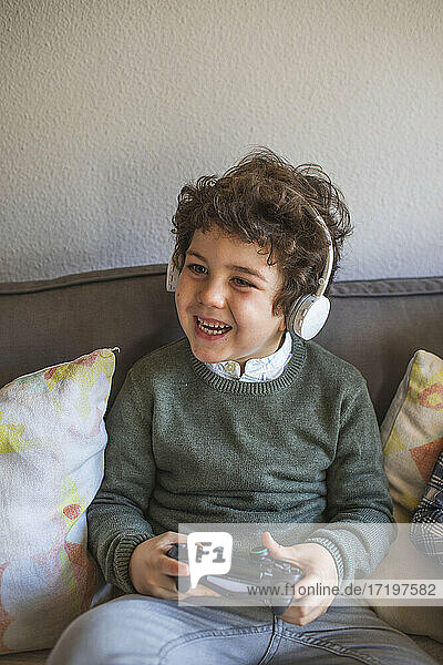 Boy with headphones plays video games very happily. Home entertainment