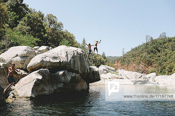 Drei Jungen springen gleichzeitig in ein kalifornisches Schwimmloch.
