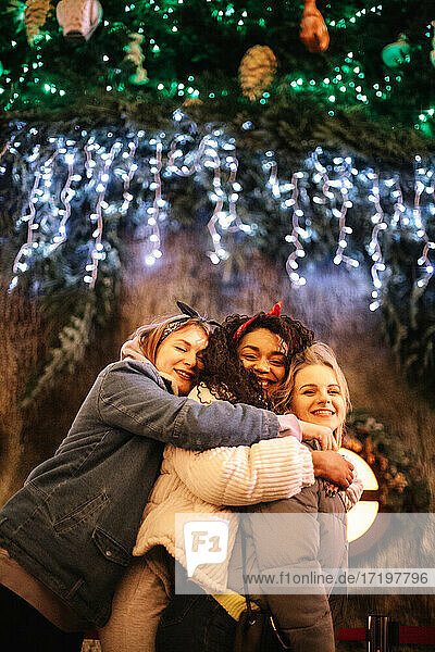 Glückliche Freundinnen  die sich in der Weihnachtszeit in der Stadt umarmen