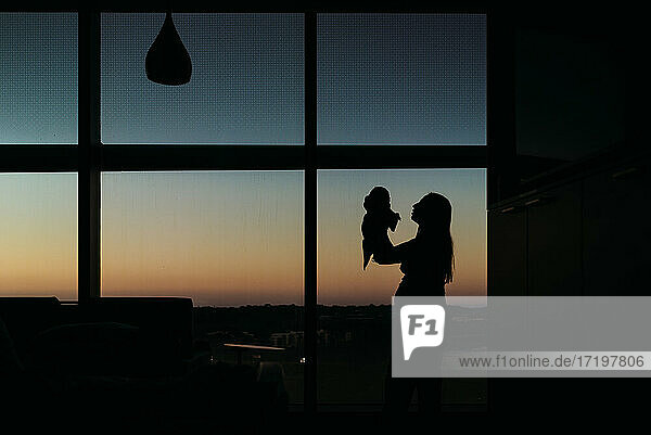 Silhouette von Mutter und Neugeborenem im Krankenhauszimmer bei Sonnenuntergang