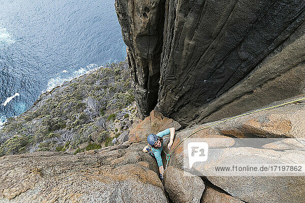 Eine Abenteurerin und Bergsteigerin klettert die Doleritklippen von Cape Raoul  Tasmanien  Australien  hinauf.