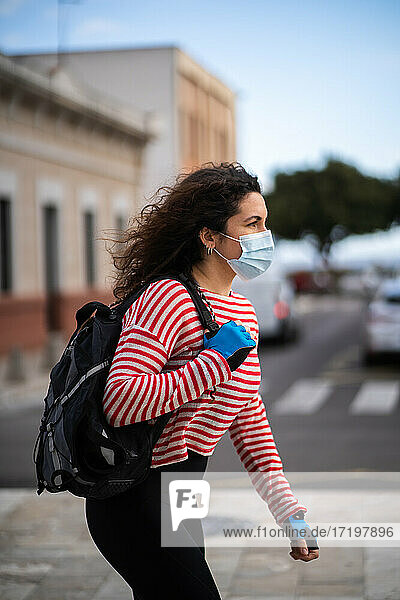 Frau mit Maske mit einer Tasche in Rollen in der Stadt