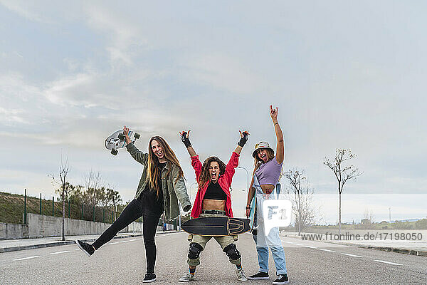 Cheerful female friends with skateboard gesturing on road