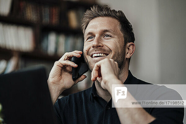 Mid erwachsenen Geschäftsmann lächelnd während des Gesprächs auf dem Handy sitzen im Café