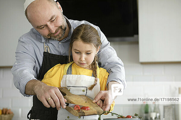 Vater unterrichtet Tochter  während er in der Küche zu Hause steht