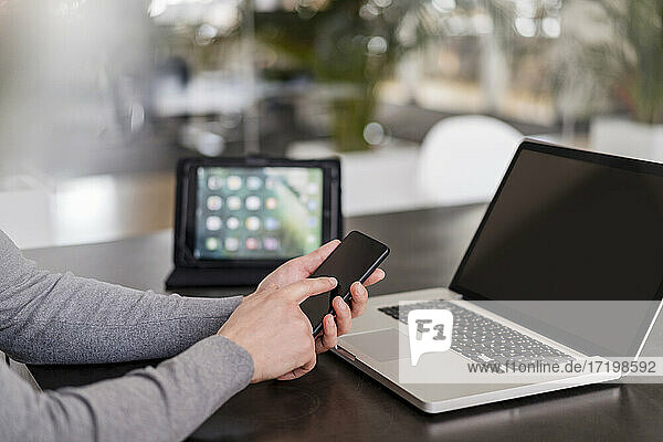 Geschäftsmann die Hände mit Smartphone durch Laptop im Büro