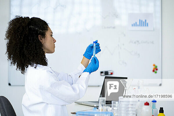 Junge Forscherin  die eine chemische Lösung in einem Reagenzglas in einer Klinik analysiert