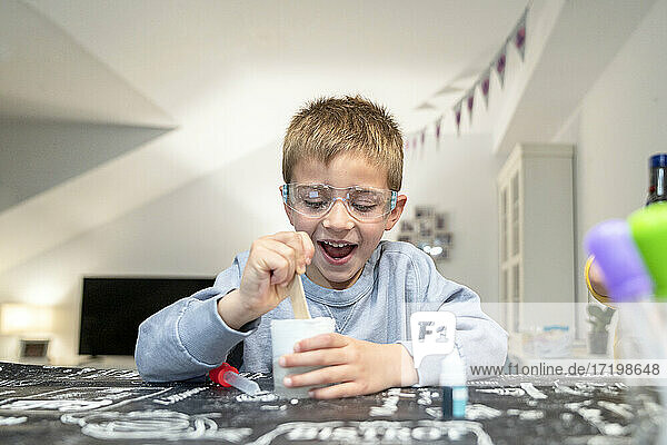 Cheerful boy playing with slime at home