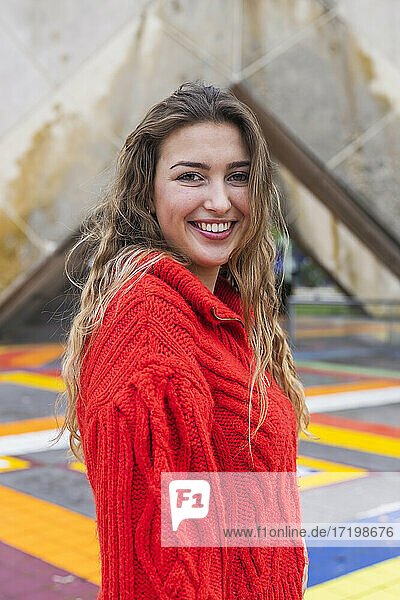 Smiling woman standing on multi colored footpath