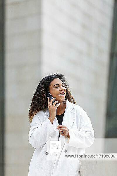 Junge Frau lacht  während sie mit einem Smartphone telefoniert