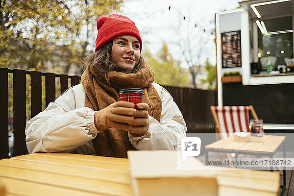 Frau mit Kaffeetasse schaut weg  während sie in einem Straßencafé sitzt