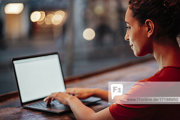 Young woman using laptop while sitting at cafe