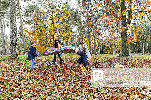 Familie mit Decke im Herbst im Wald stehend