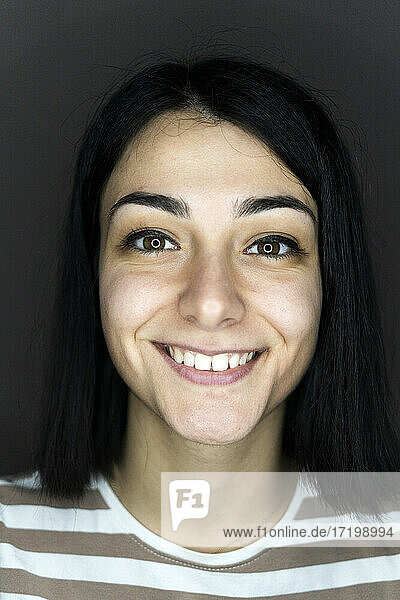 Lächelnde junge Frau mit mittellangem Haar vor grauem Hintergrund