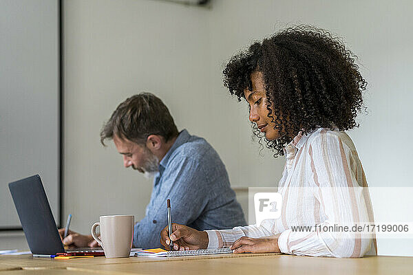 Männliche und weibliche Unternehmer bei der Vorbereitung einer Strategie während einer Sitzung im Sitzungssaal eines Büros