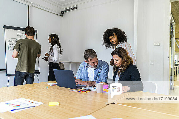Männliche und weibliche Unternehmer  die im Sitzungssaal eines Büros diskutieren