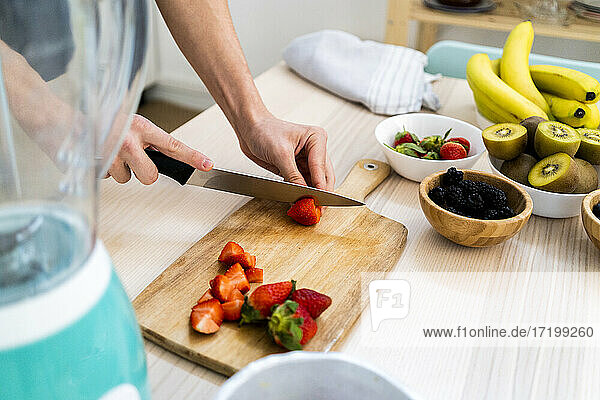 Man chopping fresh strawberries in kitchen