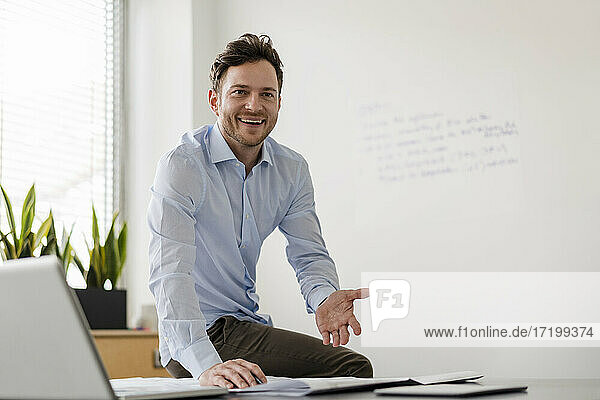 Smiling businessman with document at desk in office