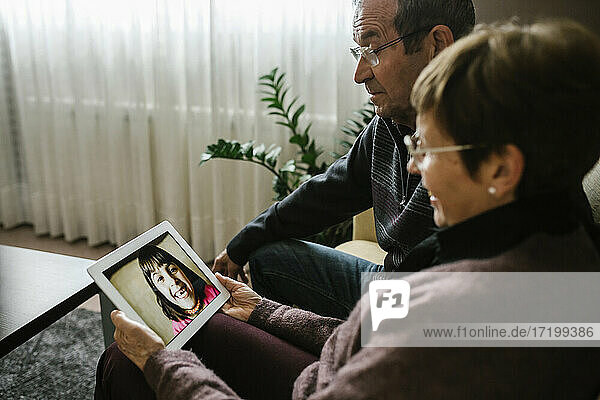 Videoanruf der Großeltern mit der Enkelin über ein digitales Tablet zu Hause