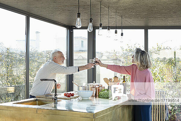 Älteres Paar stößt zu Hause in der Küche mit einem Getränk an