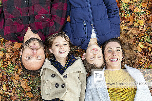 Family smiling while resting on fallen leaf in forest during autumn
