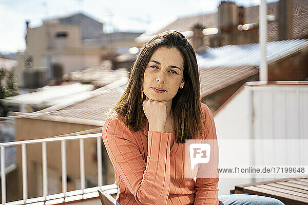 Frau mit Hand am Kinn  die auf der Terrasse sitzt und starrt