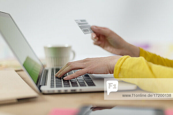 Frau zahlt mit Kreditkarte vom Laptop zu Hause