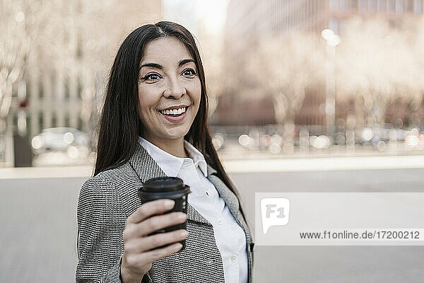 Überrumpelte Geschäftsfrau mit Kaffeetasse in der Stadt
