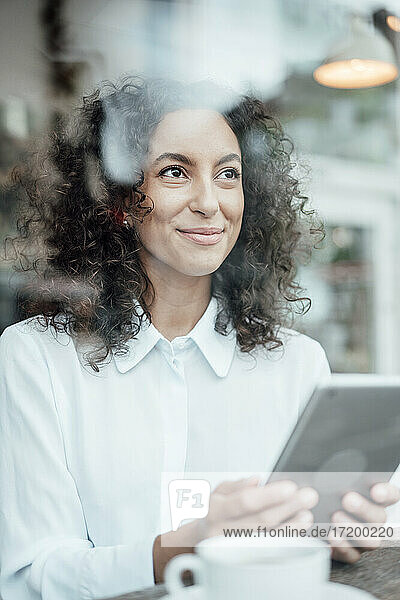 Geschäftsfrau mit digitalem Tablet  die im Café sitzt und lächelt