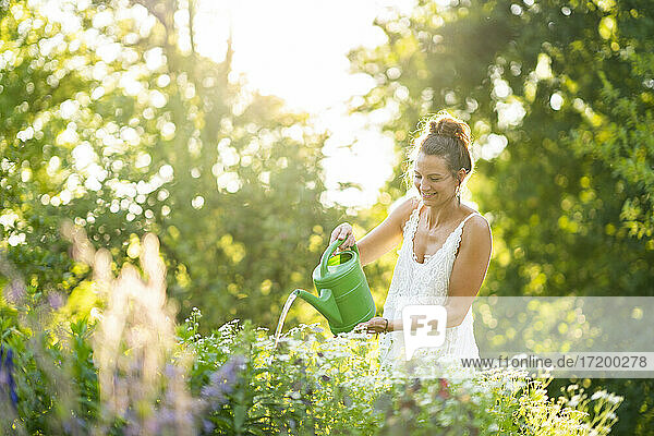 Junge Frau gießt Blumen im Frühlingsgarten