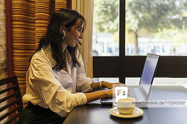 Lächelnde Unternehmerin  die einen Laptop benutzt  während sie in einem Café sitzt