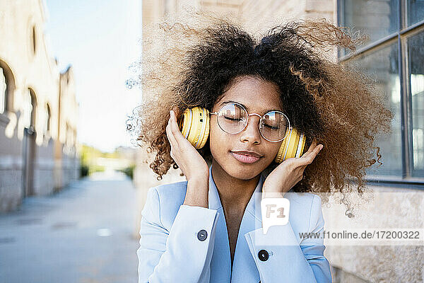 Afro-Frau mit braunem Haar hört Musik über Kopfhörer