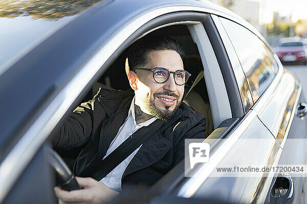 Smiling businessman looking away while driving car