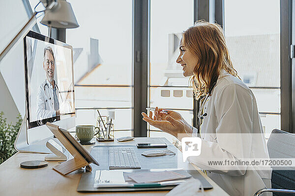 Mitarbeiter im Gesundheitswesen im Gespräch mit einem Kollegen per Videoanruf über einen Computer  während er im Büro sitzt