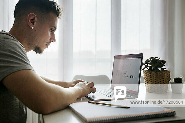 Gut aussehender männlicher Unternehmer  der im Büro zu Hause am Laptop arbeitet