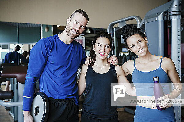 Lächelnde Sportler mit Arm um stehen im Fitnessstudio