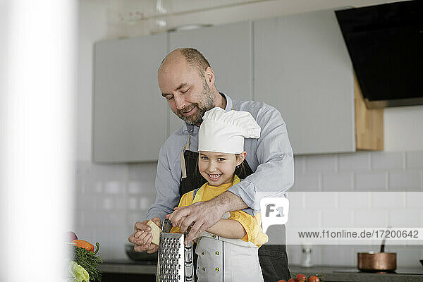 Father teaching daughter while standing in kitchen at home