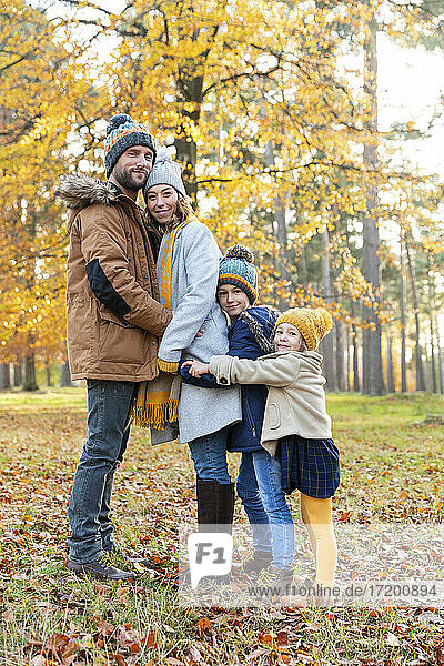 Family embracing each other while standing in forest during autumn