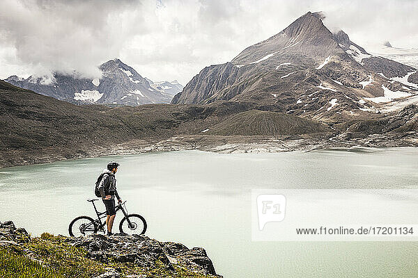 Mountain biker looking at view of Griessee lake while standing at Nufenenpass  Valais  Switzerland