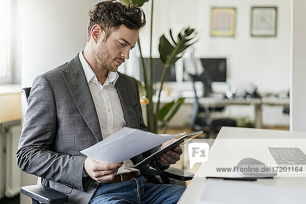 Male entrepreneur working on document and digital tablet at office