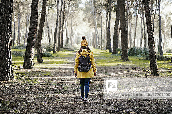 Frau im Regenmantel geht im Wald spazieren