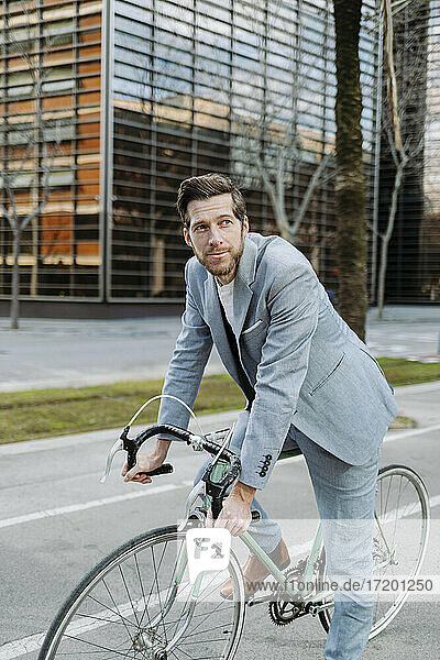 Geschäftsmann mit Fahrrad auf dem Fußweg in der Stadt stehend