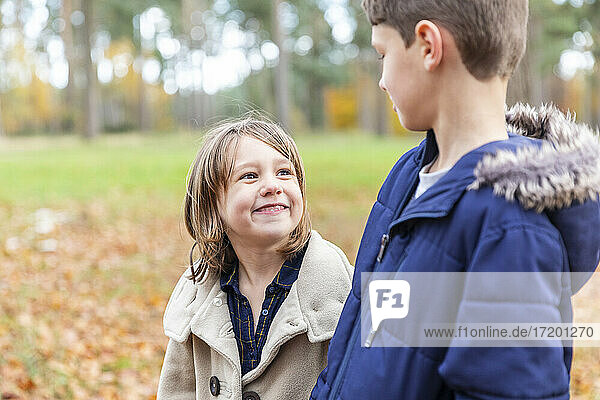 Smiling girl looking at boy while standing in forest