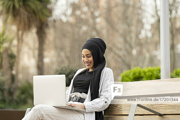 Schöne arabische Geschäftsfrau  die an einem Laptop arbeitet  während sie im Freien sitzt