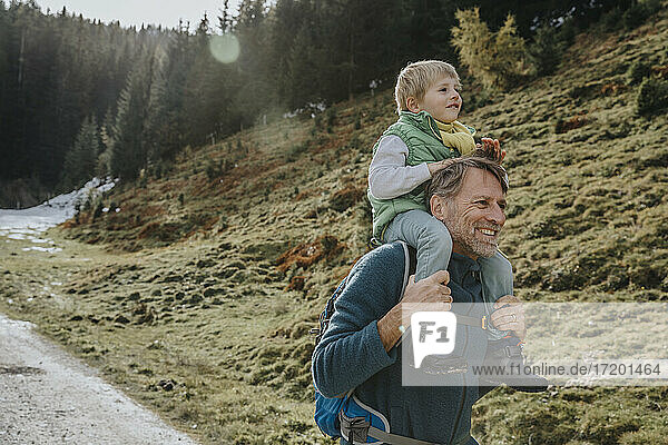 Vater trägt Sohn auf der Schulter bei einem Waldspaziergang im Salzburger Land  Österreich