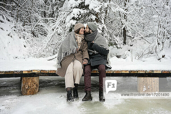 Paar schaut sich an  während es auf einer Brücke im Wald sitzt